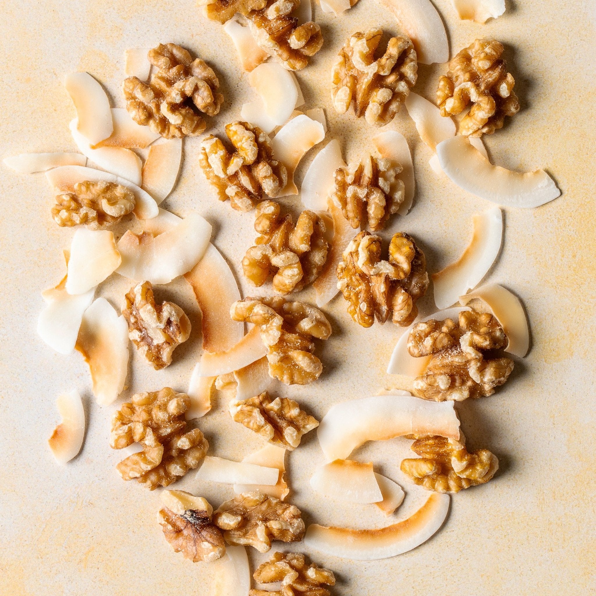 Organic coconut and walnut granola ingredients — oats, coconut flakes, walnuts, maple syrup